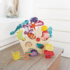 Sentence with product name: A colorful wooden puzzle shaped like a Stacking Coral Reef, featuring various sea creatures such as fish, starfish, and shells, placed against a light indoor background.