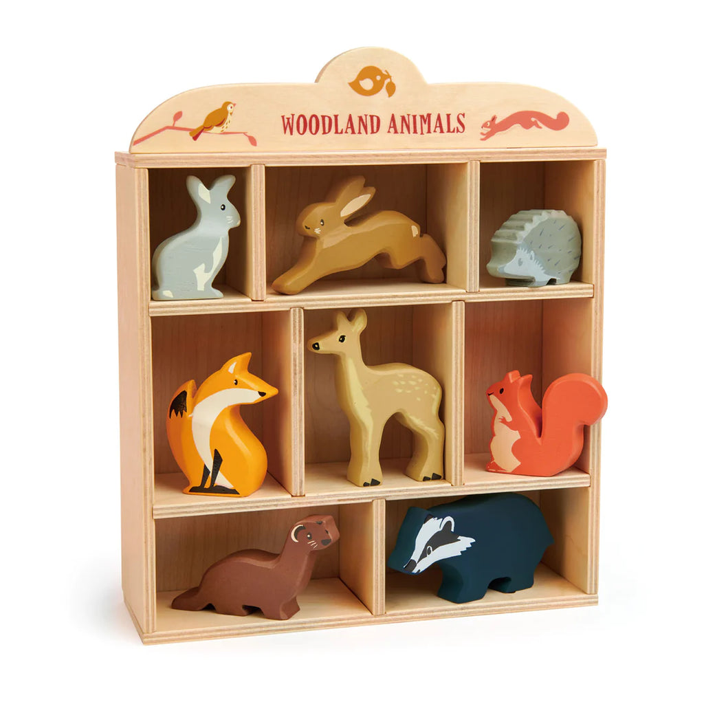 A wooden animal display stand labeled "Woodland Animals Set" containing eight colorful wooden animal figures: a rabbit, deer, fox, squirrel, bear, hedgehog, otter, and bird.