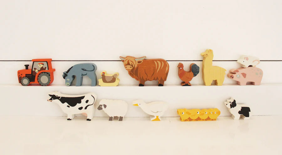 A collection of colorful wooden Farmyard Animals Set made from sustainably sourced rubberwood, arranged on a shelf, including a tractor, elephant, cow, pig, and chicken, set against a white background.