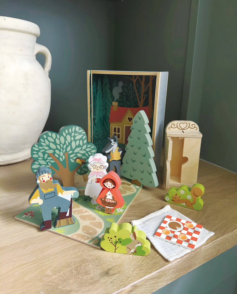 Your Story of Little Red Riding Hood is a colorful playset with wooden standing figures, house, trees, bed, picnic blanket, and woodland backdrop—all stored neatly in a sturdy plywood box for easy organization.