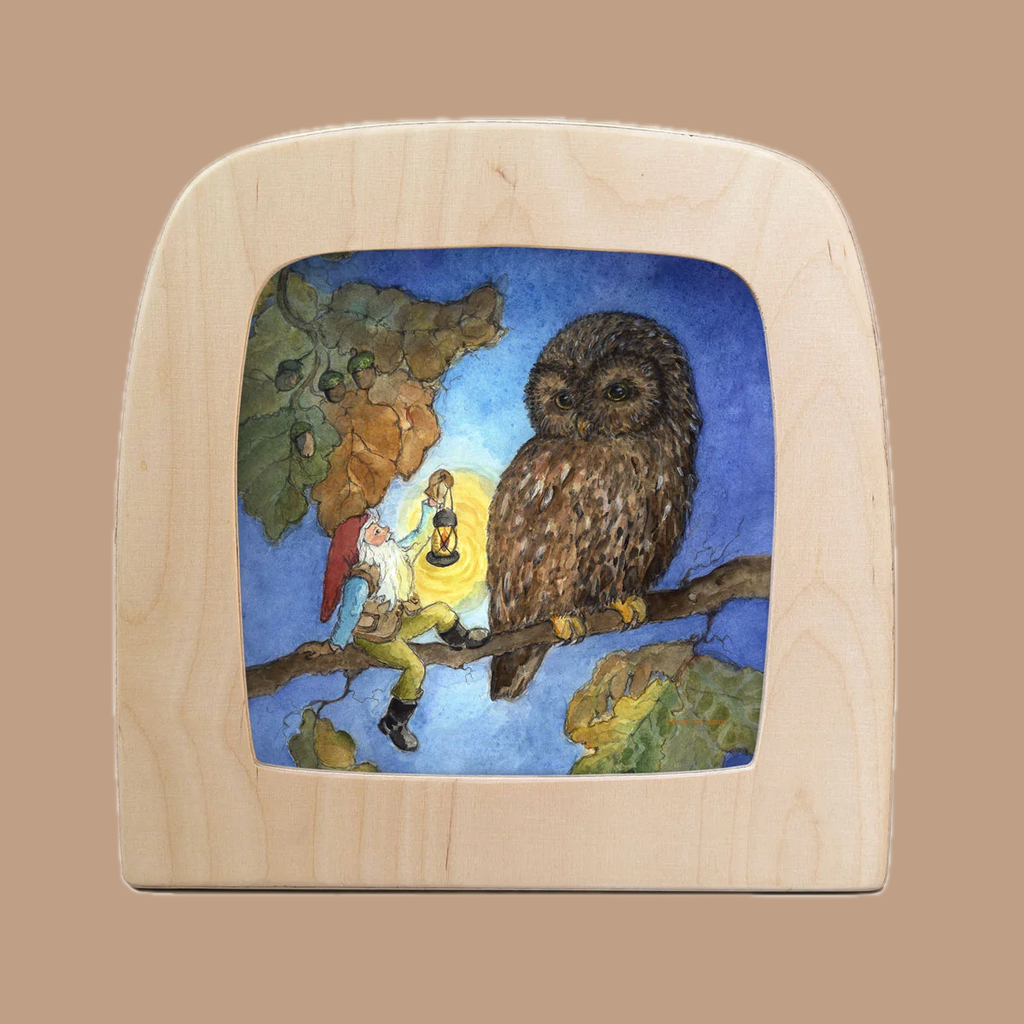 The "Silhouette Only - Night Owl" features a small figure in red and blue offering light to a large owl on a branch, highlighted against the night sky with encircling leaves. The frame is crafted from light, curved wood.