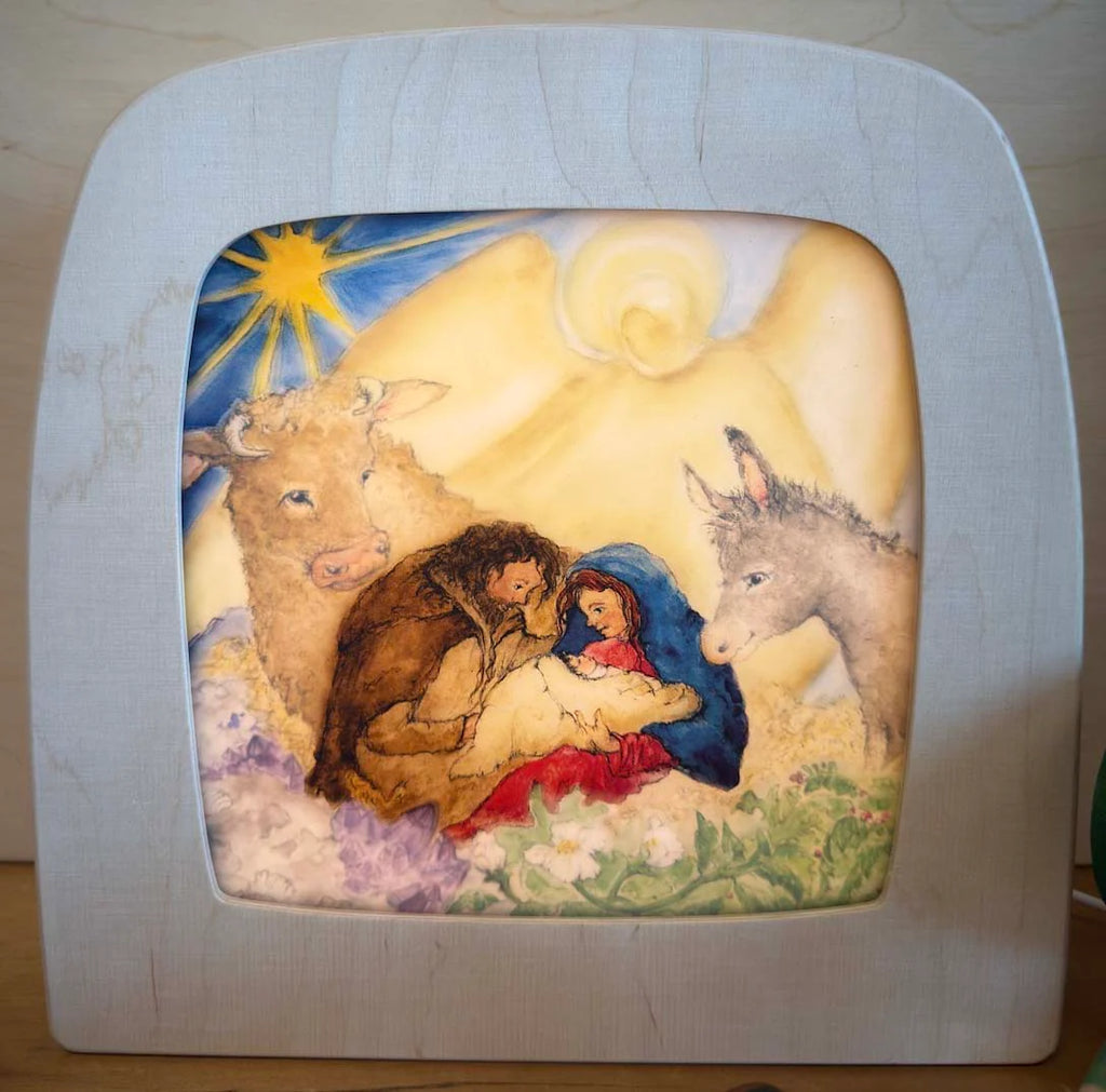 This set of 4 "Silhouette Only - Layered Light: An Advent Story" slides for the Toverlux Lamp features recycled PET silhouettes of the Nativity—Mary, Joseph, baby Jesus, cow, and donkey beneath a star and angel in a light wooden arch.