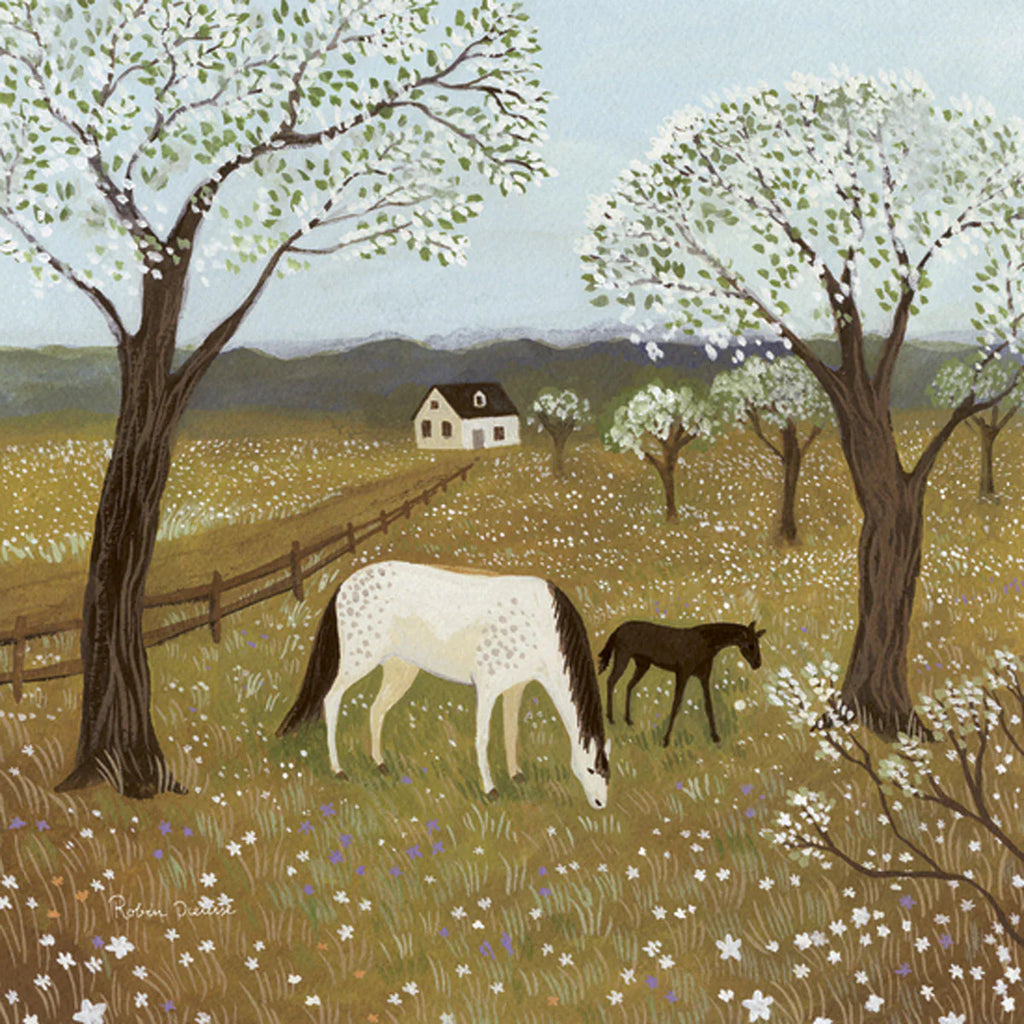 A serene countryside scene with a white horse and a black foal grazing amidst a field of wildflowers. Tall trees with white blossoms are scattered throughout the meadow. In the background, a white house adorned with Spring Frolic Silhouettes from the Toverlux Lamp collection stands against rolling hills, exuding rustic charm.