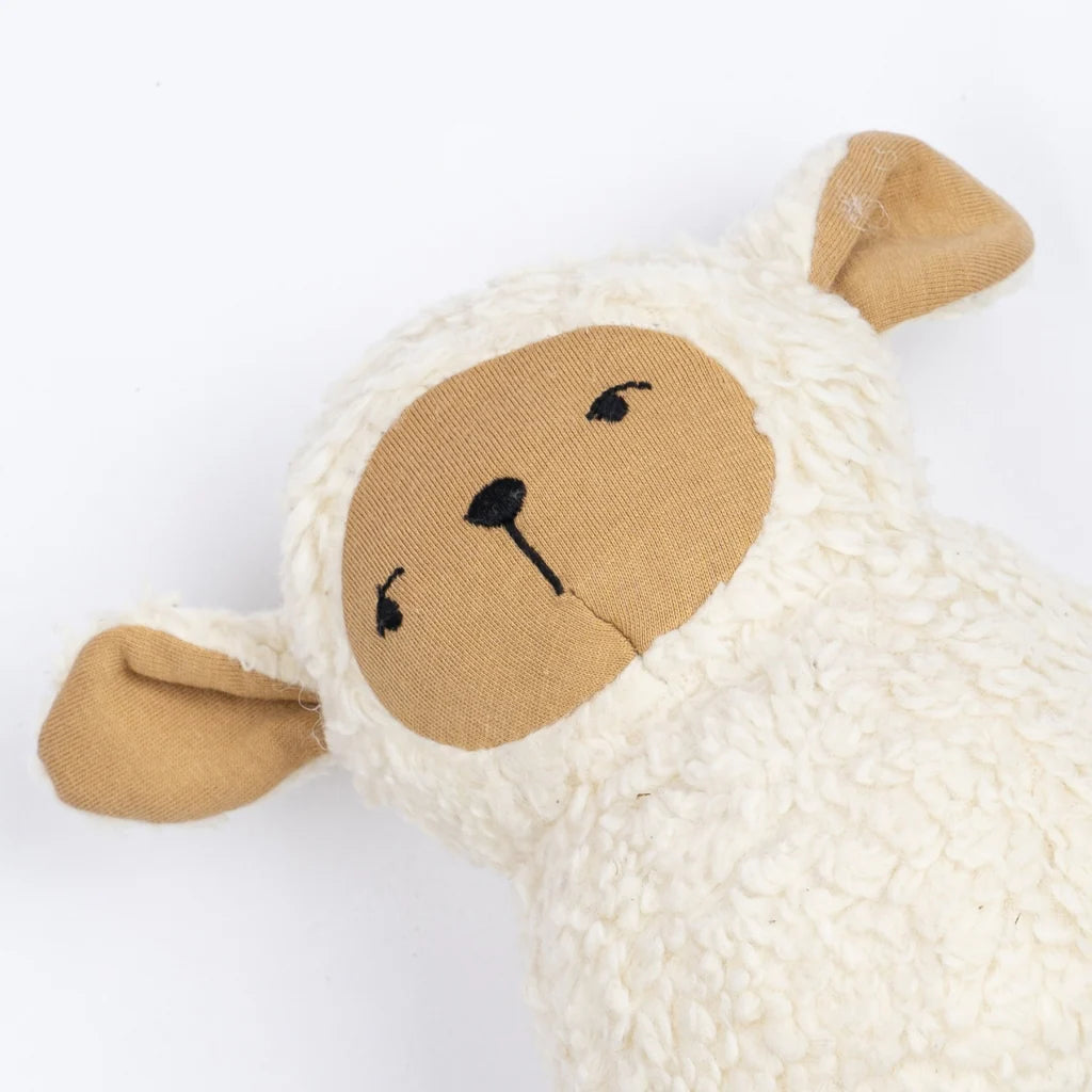 The Organic Cotton Sheep Tumbler features a soft, plush body, beige face and ears, closed embroidered eyes, and a gentle expression. Its white textured surface encourages sensory exploration and offers comfort to little ones.