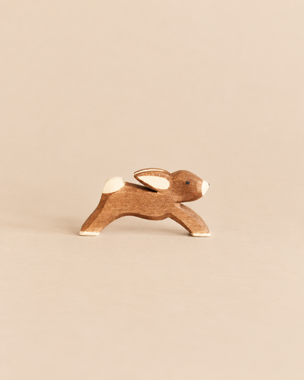 Ostheimer Rabbit - Running, a handcrafted wooden toy rabbit in a running pose with white accents on its ears, tail, and paws, perfect for imaginative play.