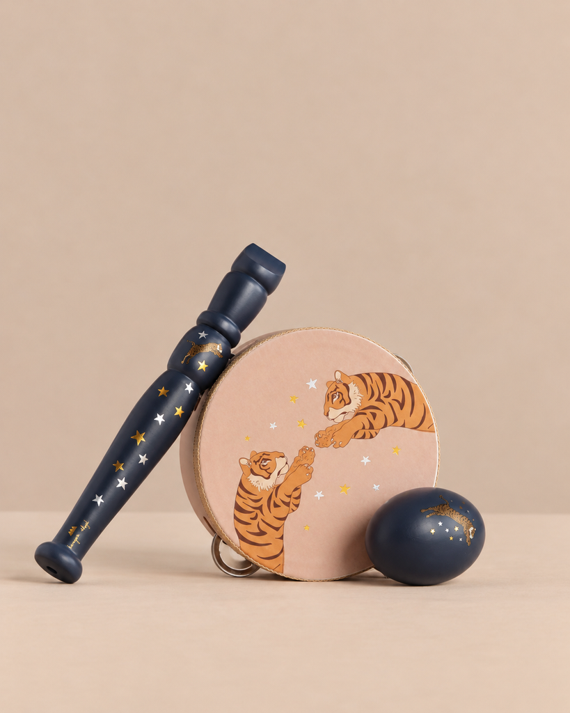 The Konges Sloejd Music Set Petite - Tiger includes a wooden tambourine with a tiger and stars illustration, a dark blue maraca, and a matching egg shaker.