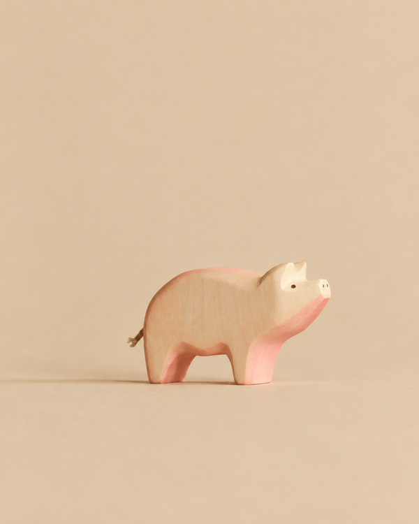 A Handmade Holzwald Pig minimalist wooden figurine featuring pink-tinted accents, crafted as a sustainable toy.