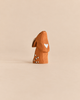 A Bumbu Handmade Wooden Curious Rabbit, featuring a brown finish with a white heart on its chest and white spots on its back, perfect for an Easter basket.