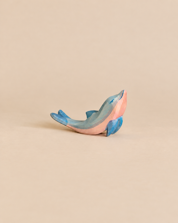 A handcrafted Ostheimer Dolphin, Head High, painted in shades of blue and pink.