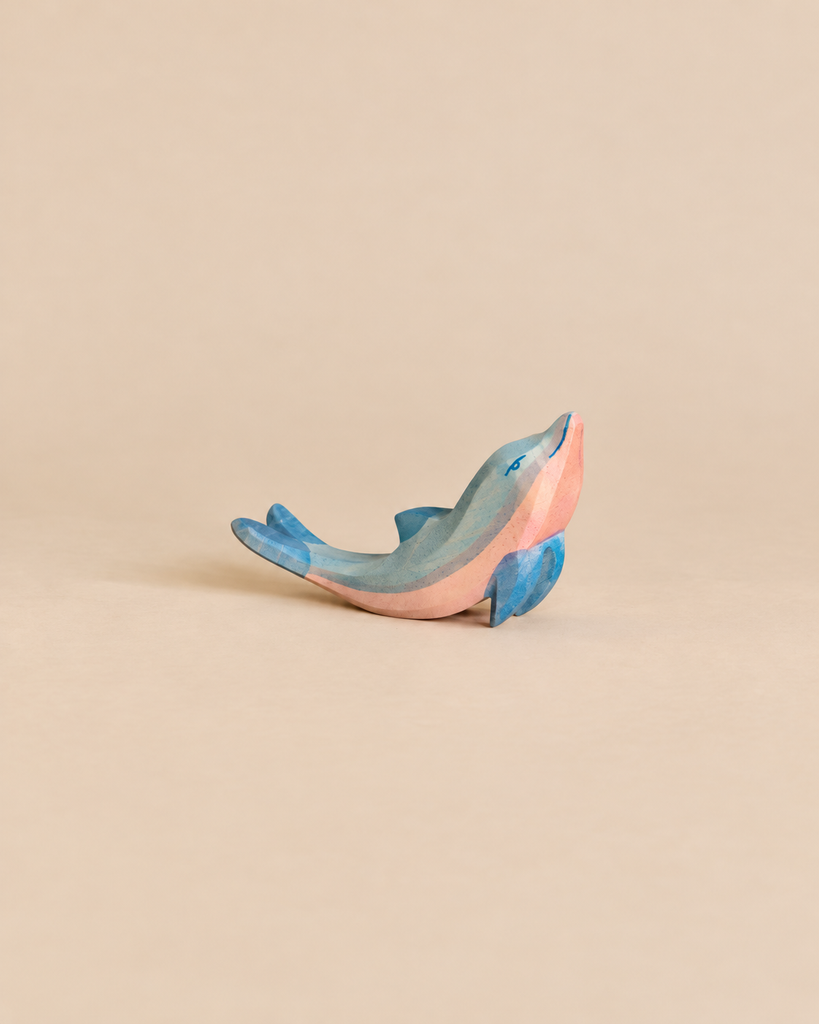 A handcrafted Ostheimer Dolphin, Head High, painted in shades of blue and pink.