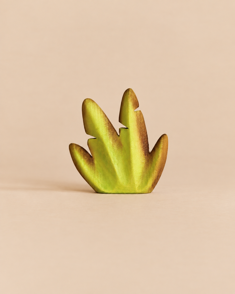 Small Bumbu Handmade Wooden Banana Bush toy shaped like a stylized green prehistoric plant leaf.