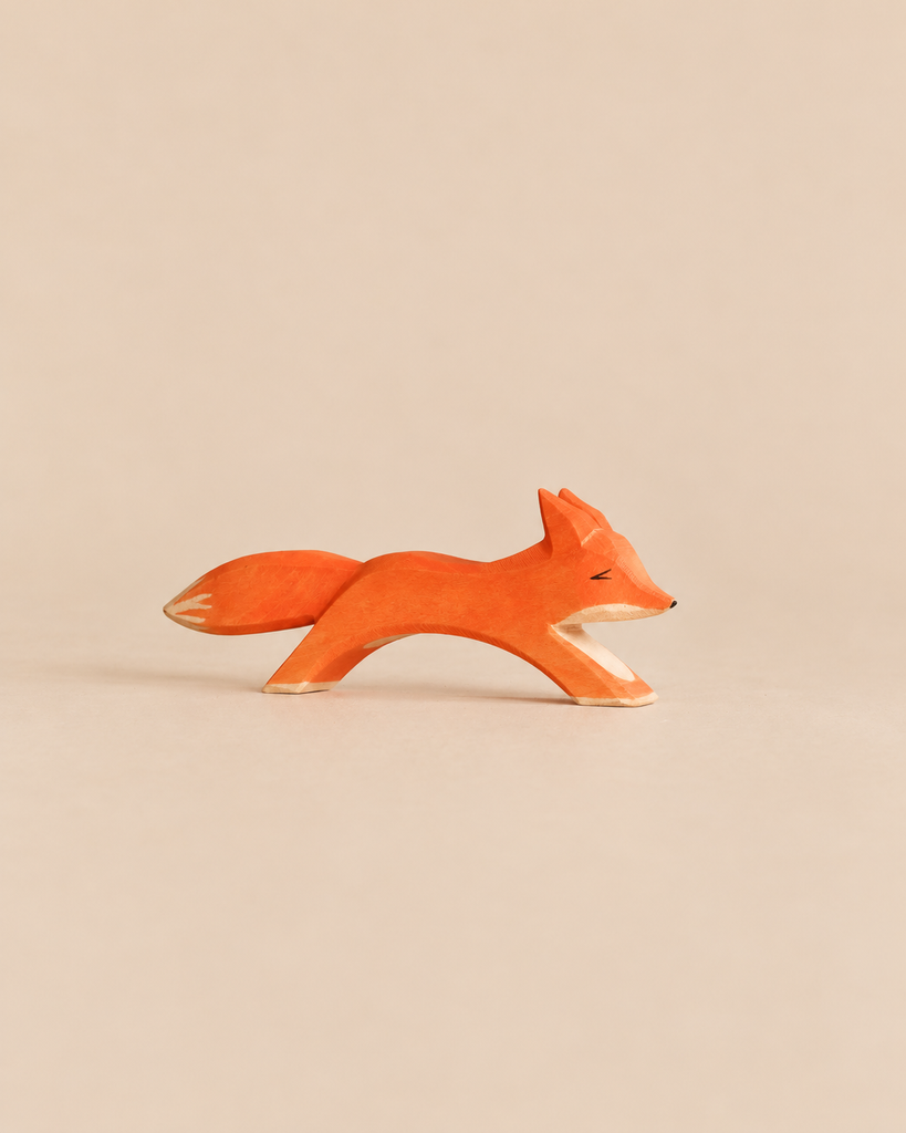 Ostheimer Fox - Running: a handcrafted wooden toy fox in a running pose with an orange body and white-tipped tail.
