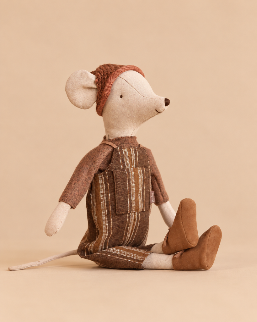 A Maileg Medium Mice Set toy mouse wearing a brown knitted cap, a long-sleeved shirt, striped overalls, and felt shoes.