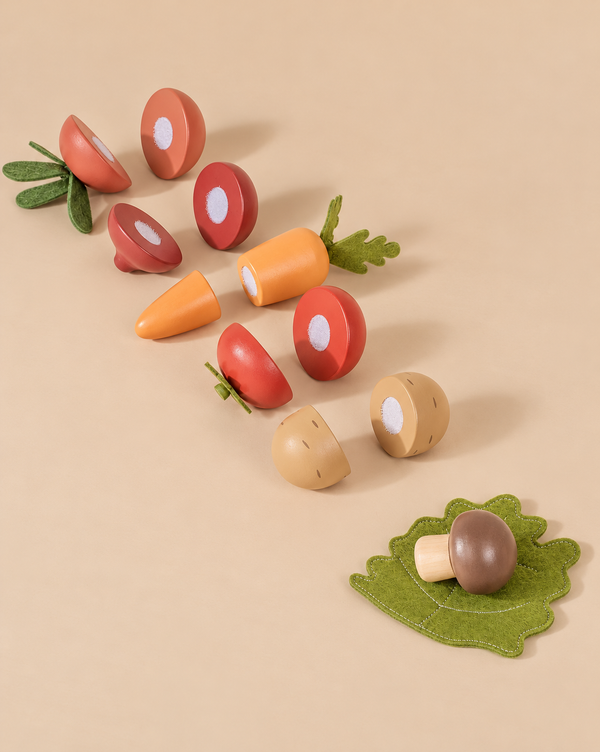 Sliceable Wooden Vegetables, including a tomato, carrot, radish, and mushroom, arranged on a flat surface with a felt leaf.