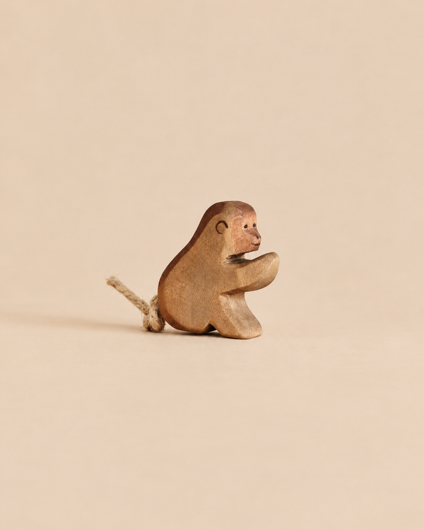 A small, handcrafted wooden Ostheimer Baboon, Sitting with a short rope tail.