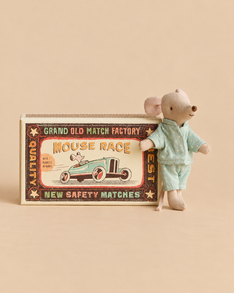 A Maileg Breakfast Table Set featuring a Maileg mouse in blue polka-dot pajamas standing next to a decorative “Mouse Race” matchbox.