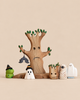The Handmade Bumbu Haunted Tree Halloween Set features a wooden tree with a hanging bat ornament, surrounded by sustainable Waldorf figures including ghosts, a mummy, and a green creature, all wearing black witch hats.