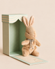 A small brown Maileg My First Bunny - Brown plush toy sitting next to its open, light-blue patterned baby gift box.