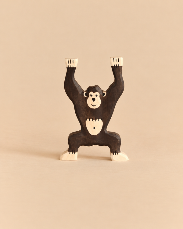 A handcrafted wooden Holztiger Chimpanzee, Standing toy with its arms raised.