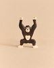 A handcrafted wooden Holztiger Chimpanzee, Standing toy with its arms raised.