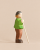 Handmade Holzwald Shepherd figurine of a person wearing a green tunic, brown trousers, and a grey cap, holding a tall staff.