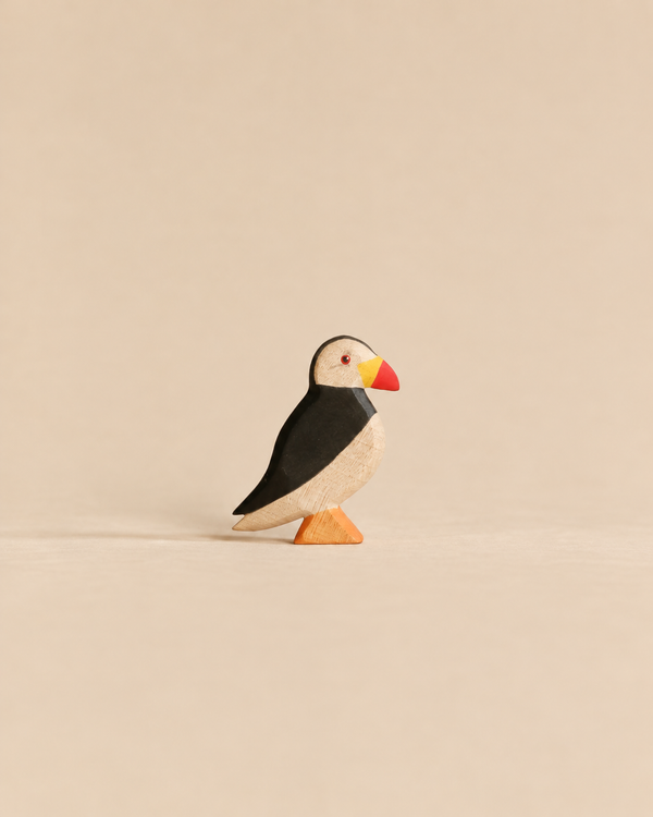 Handmade Holzwald Bird - Puffin, a small, sustainable wooden figurine with black, white, and red coloring standing on an orange base.