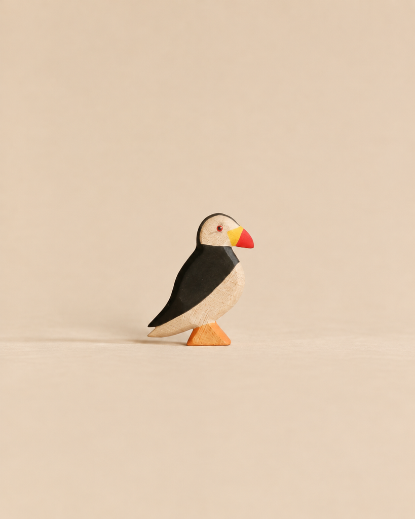 Handmade Holzwald Bird - Puffin, a small, sustainable wooden figurine with black, white, and red coloring standing on an orange base.