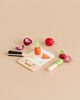 Mini Chef Chopping Board featuring a sustainable rubber wood cutting board, a wooden knife, and toy fruit and vegetables including a carrot, onion, and beet.