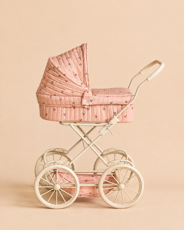 Konges Sloejd Doll Pram - Cherry Blush in a vintage style with a cherry print, featuring a quilted hood, cream frame, and four large wheels.