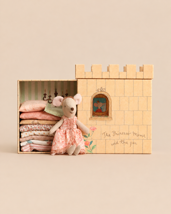 A Maileg Princess and The Pea, Big Sister Mouse in a floral dress sits beside a castle tower box containing a stack of small mattresses.