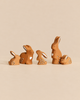 Five Bumbu Handmade Wooden Brown Bunny Rabbit Family Set figurines of varying sizes, each featuring painted white accents on their ears and bodies as a charming nature-inspired play set.