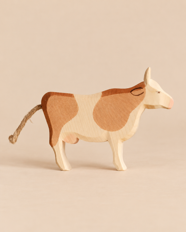 Ostheimer Cow - Standing, a handcrafted wooden toy with brown patches and a rope tail, perfect for imaginative play.