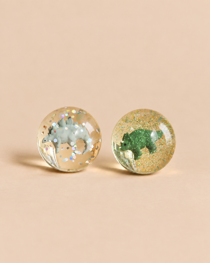 Two clear Konges Sloejd Glitter Bouncing Ball Set - Dinosaurs bouncing balls containing glitter and miniature dinosaur figures.