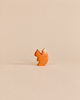 A small, handmade wooden squirrel with an orange body and a white-tipped tail from the Handmade Holzwald Woodland Animals Set.