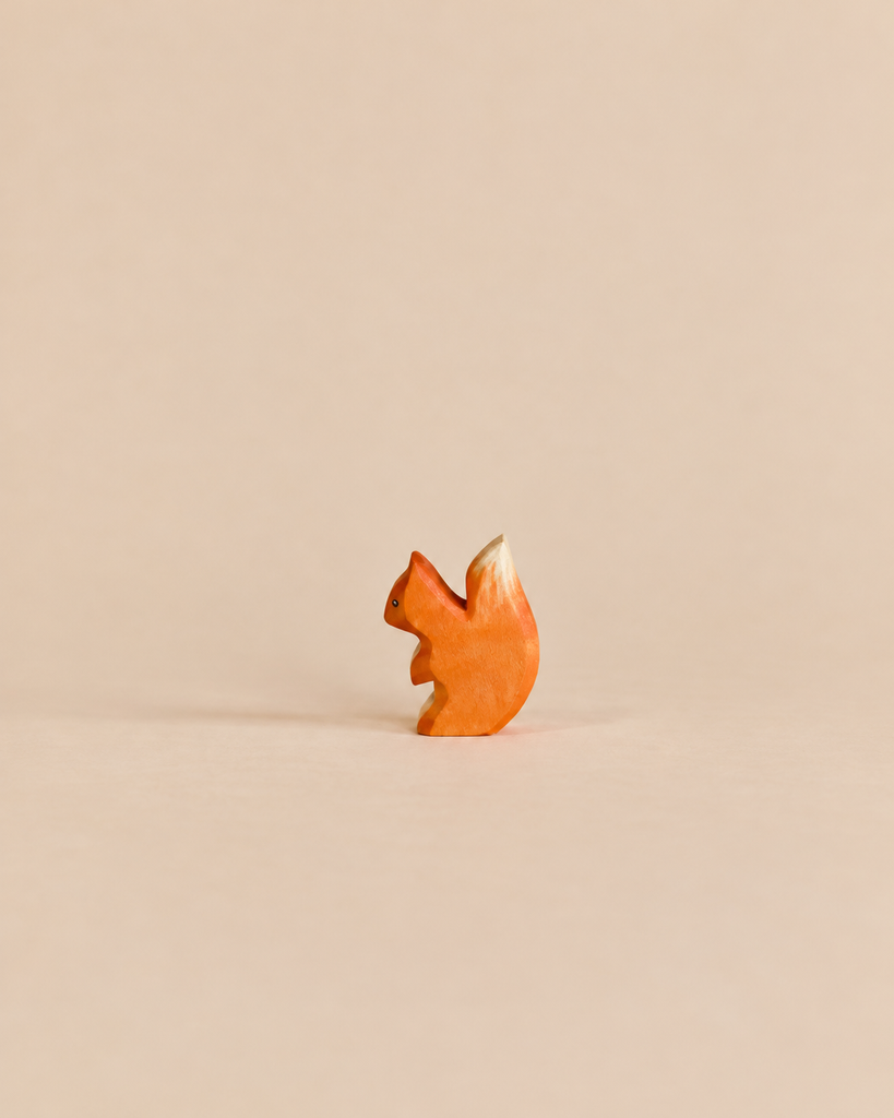 A small, handmade wooden squirrel with an orange body and a white-tipped tail from the Handmade Holzwald Woodland Animals Set.