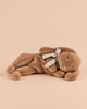 A soft brown Maileg Plush Sleeping Bunny - Soft Brown lies on its side, wearing a small floral ribbon around its neck.