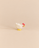 An Ostheimer White Hen - Standing handcrafted as a small wooden toy with a white body, red comb, and yellow feet, perfect for imaginative play.