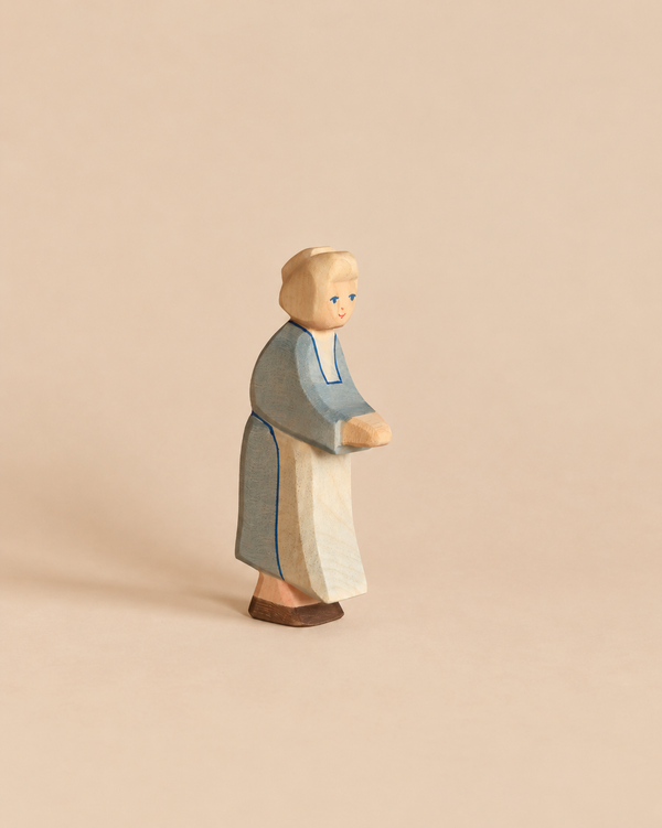 Hand-painted Ostheimer Grandmother wooden figurine of a woman in a blue dress and a light-colored apron, depicted in profile.