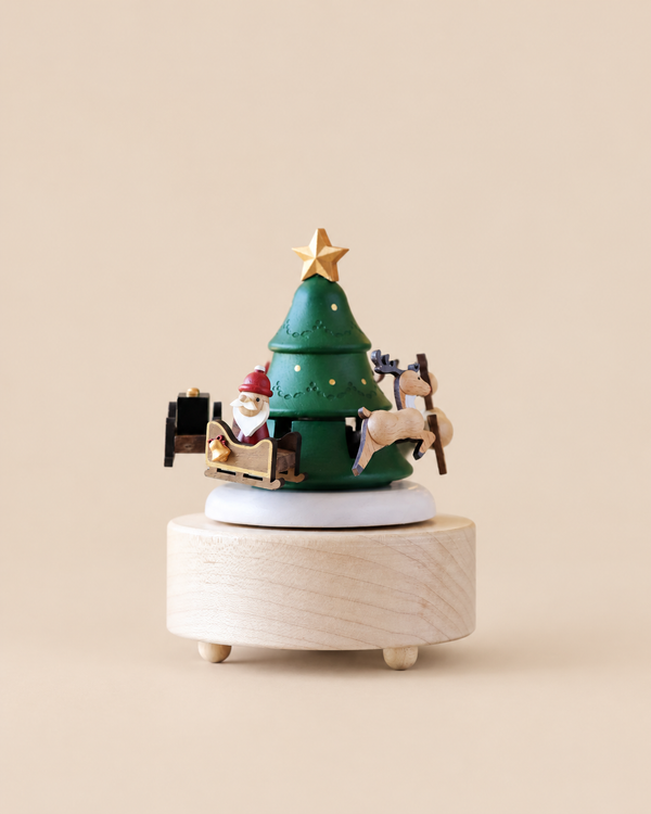 The Santa & Reindeer Music Box features a green Christmas tree with a star topper, surrounded by a rotating Santa Claus in a sleigh and a reindeer.