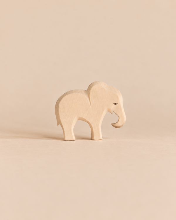 An Ostheimer Small Elephant - Eating, a small, handcrafted wooden elephant figurine with its trunk pointed downward.