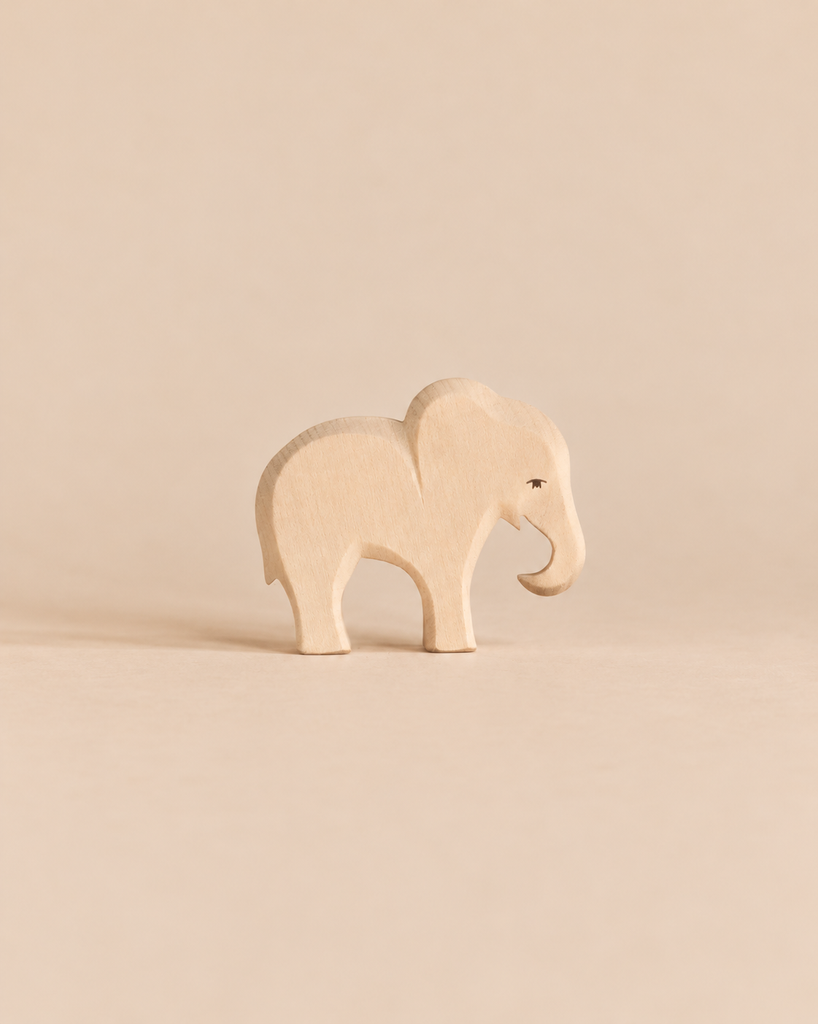 An Ostheimer Small Elephant - Eating, a small, handcrafted wooden elephant figurine with its trunk pointed downward.