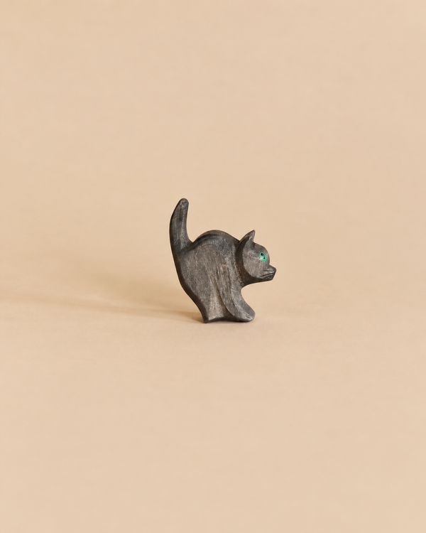 Small black Ostheimer Cat For Witch wooden figurine with a raised tail and a single green eye.