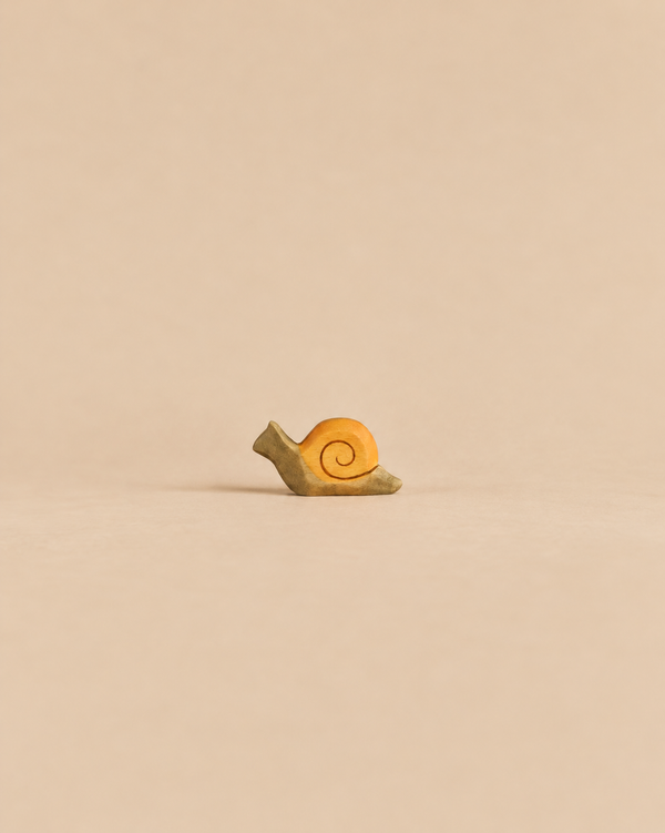 A small Handmade Holzwald Snail, Small with a tan body and a yellow spiral shell.