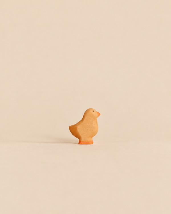 Handmade Holzwald Baby Chick, a small wooden figurine of a baby chick with an orange beak and feet, crafted as a sustainable toy.