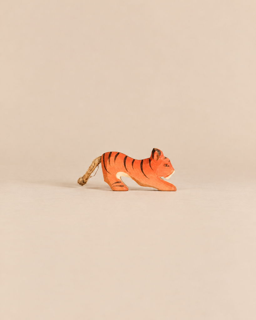 Ostheimer Tiger Lurking, Small, a handcrafted wooden tiger figurine in a pouncing pose with a rope tail.