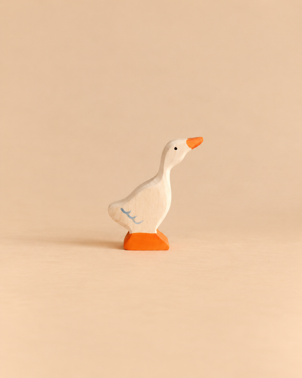 A small Holztiger Goose, Small wooden figurine with an orange beak and feet, and a blue feather detail on its side, perfect for open-ended play.
