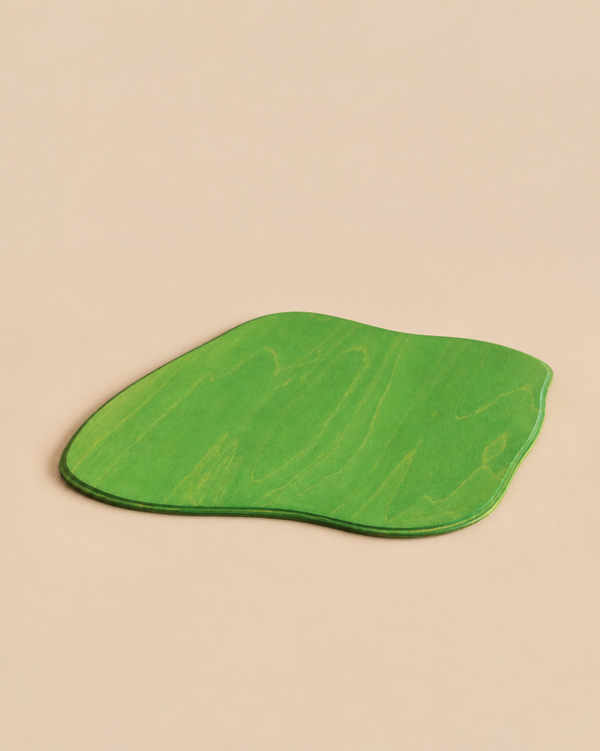 An Ostheimer Meadow Plate, Large, featuring a green, flat, organic-shaped wooden board with wavy edges.