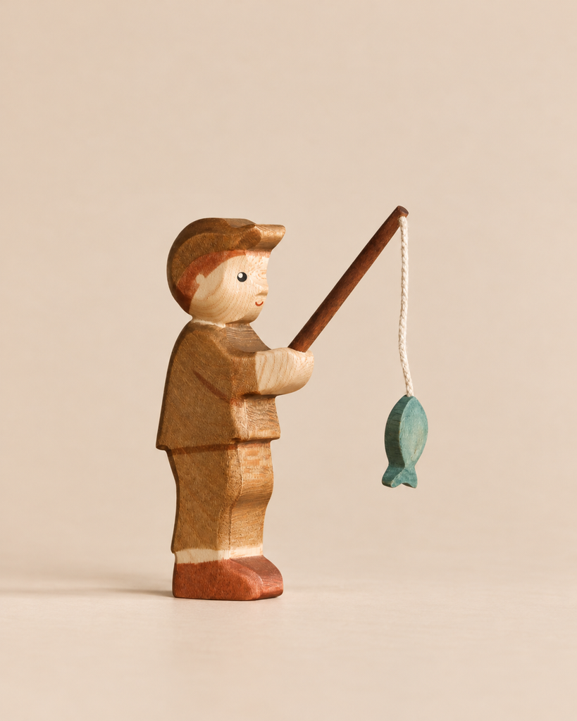 Handmade Holzwald Fisherman wooden toy wearing a cap and holding a rod with a small green fish hanging from a string.