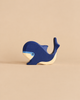 A handcrafted Holztiger Blue Whale toy with a dark blue body, light blue facial details, and a natural wood-colored underside.