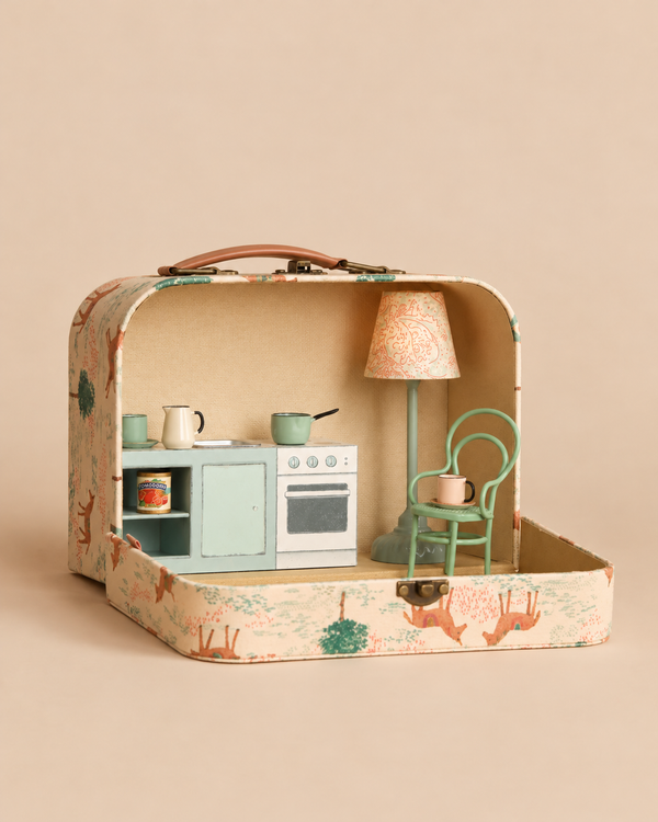 An open patterned Maileg On The Go Kitchen Suitcase Set containing miniature kitchen furniture including a stove, sink, vintage floor lamp, and chair.